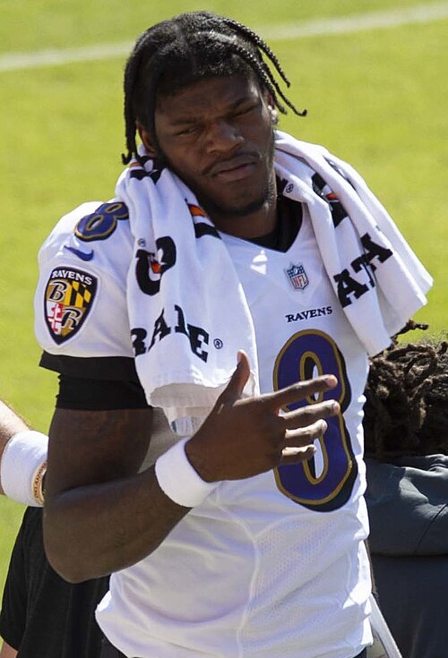 Lamar Jackson wearing a Baltimore Ravens uniform with a towel over his shoulders in 2020. Player photograph, not card artwork.