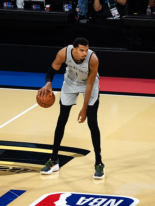Victor Wembanyama dribbling in a San Antonio Spurs uniform at the 2025 NBA Cup. Player photograph, not card artwork.